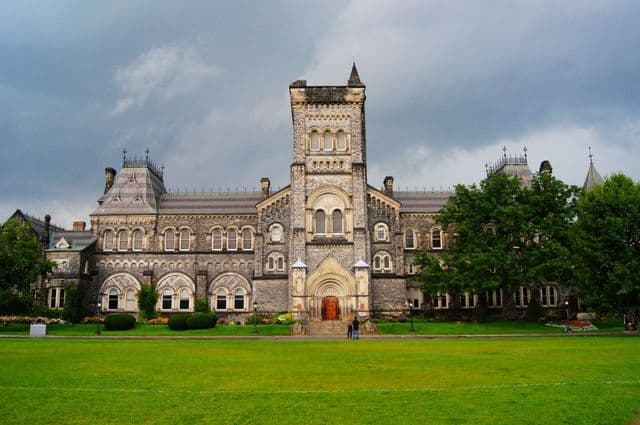 Gothic Revival university building surrounded by greenery in Toronto, Canada