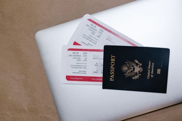 Passport and boarding pass placed on a laptop keyboard, representing UK student visa travel preparation